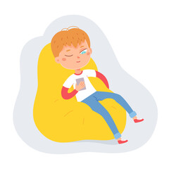 Tired child with mobile phone sitting in bean bag chair, cute little boy using smartphone