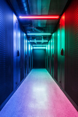 Cold aisle of an IT server room with perforated grille doors illuminated in color and large cooling...