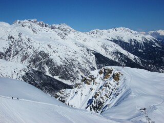 View of mountains and ski slopes in Les Sybelles, France. Snow capped peaks against blue sky. Sunny...