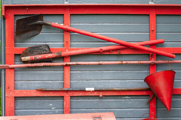 Red shovels and a bucket on the blue wall. Old fire fighting equipment