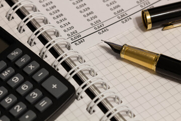 Financial report, a fountain pen with cap and paper with numbers on the table in the office. A paper sheet full of business data. Accounts number on the data paper. Business documents. Close-up