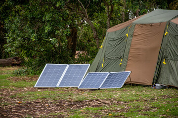 Portable foldable solar panels and Tent at the campsite surrounding by nature. Camping and...
