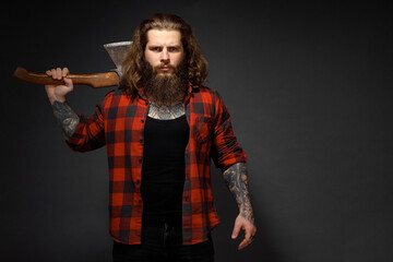 handsome man with long hair with an ax in his hands on a dark studio background