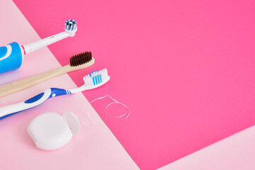 dental floss, electric, bamboo and plastic toothbrushes on a pink background, which brushes are more effective