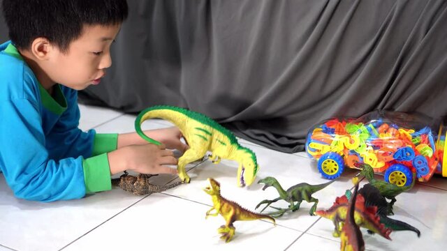 A kid play dinosaur toy at floor.