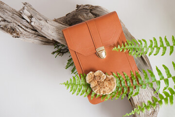 brown bag made of eco leather, mushrooms and fern on a gray background