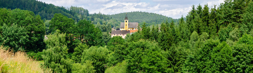 Fototapeta premium panorama of a wooden landscape with the church of a small vilage in the center in the region Waldviertel (forestquarter) Austria