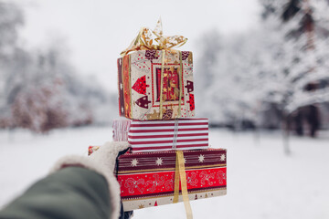Close up of heap of red Christmas presents gift boxes in snowy winter park outdoors. Festive...