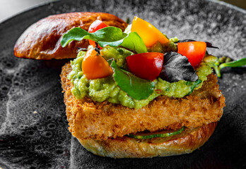 Vegetarian open burger with grilled tofu, guacamole sauce and vegetables in plate 