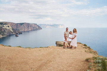 Fototapeta premium big family against the backdrop of a beautiful seascape. everyone hugs together. mom is pregnant. two little sons and dad. the large family