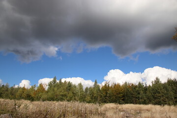 A dark cloud above the beautiful blue summer sky in the nature with meadows and forest near Kaproun, Czech republic