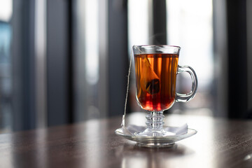 Tea infusion in a bag in a glass cup, on a blurred background. Place for inscription