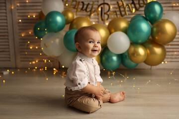 Cute blond kid in a festive shirt and trousers. A happy kid on the background of balloons with...