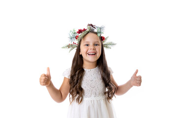 portrait of smiling, charming girl in Christmas wreath, white dress and giving thumbs up, isolated on white background with copy space. 
