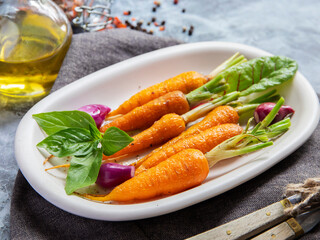 baked roast baby carrots in a plate, basil and spices vegan dish close up
