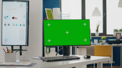 Close up of monitor with green screen at empty desk. Nobody in startup office with chroma key and...