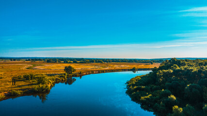 Aerial  view of a beautiful summer  landscape over river while dawn. Top view over river with a smooth water surface reflecting blue sky.