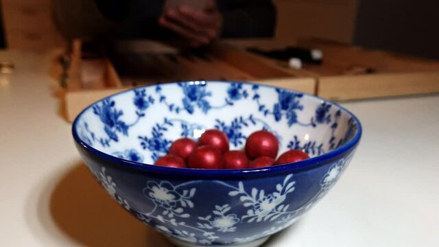 A bowl of marsipan chocolates and a hand.
