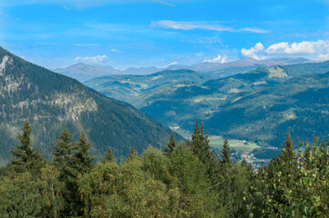Fototapeta na wymiar Bergige Landschaft in Österreich. Blick von einem hochgelegenen Punkt auf eine Gebirgskette. Sonniger Herbsttag