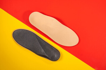 Foot support and healthy feet concept with orthopedic shoe insoles isolated on color background