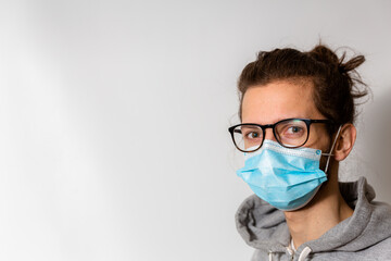A young man in glasses wearing a medical one use facemask during the Covid-19 corona virus pandemic