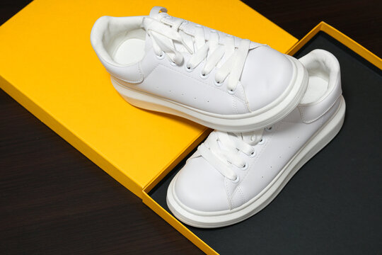 White new sneakers.  dark, orange  background. Lifestyle sneaker sport shoe.