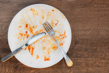 dirty plate after eating.  fork and knife on a plate. Dirty dish after eating.