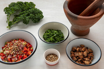 Fresh cut vegetable ingredients to make meal using clay mortar for kale leaves.