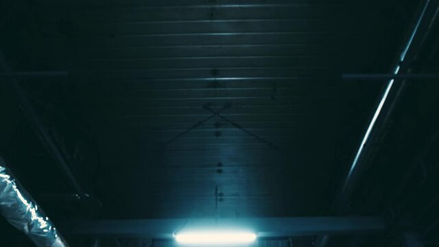 Contemporary elevator goes up long dark shaft with built-in bright lights on metal construction illuminating empty space