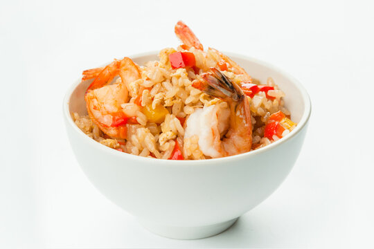 Asian rice with tiger shrimp, bell pepper, onion, carrot and scrambled egg served in white bowl. Dish isolated on white background. Copy space image
