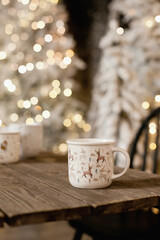 A cup of coffe with christmas tree lights bokeh as background. Holiday season coffee break.