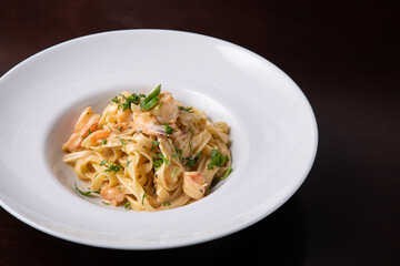 Italian pasta with prawns chili pepper and greens. Italian food, white dish, dark background