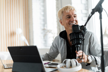 Communicates with people through a microphone. Radio host age male works in a recording studio.