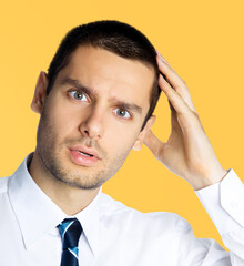 Portrait of puzzled, shocked, astonished businessman in white shirt and tie, isolated over orange yellow colour background with copy space area. Confident business man at studio image.