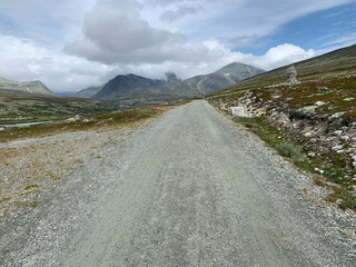 Schotterweg zu den Bergen bei bewölktem Himmel