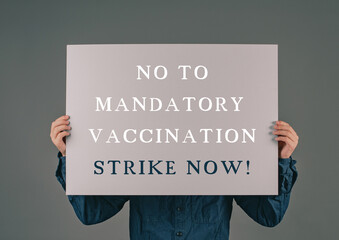 The words stop mandatory vaccination are standing on a paper, protest anti covid-19 vaccine,...