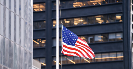 The national flag of United States of America winding between the tall skyscraper buildings from Manhattan, New York. Patriotism symbol..