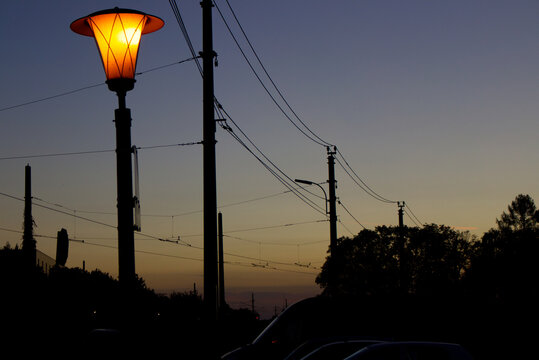 electrical lines and a street lantern during sunset at a small tainstation