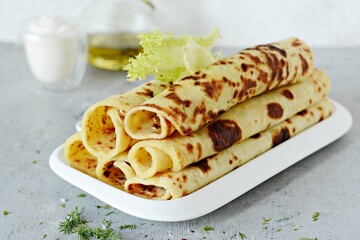 Norwegian potato pancakes Lefse on a light background with cheese and greens. Traditional Scandinavian cuisine.