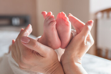 Naklejka premium Mother hugs legs of newborn baby with hands