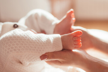 Mother hugs legs of newborn baby with hands
