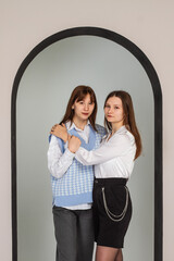 Two girls, girlfriends, sisters hug each other, stand next to shooting in the studio