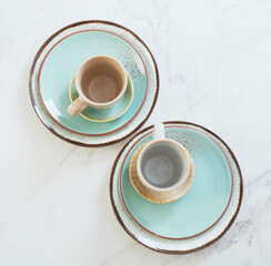 two ceramic cups and plates on white marble table