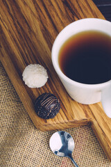 White cup of black tea with spoon and candy on wooden desk. Sweet dessert with tea concept