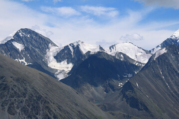 The peaks of the high-mountain Katunsky ridge near Belukha, glaciers on the peaks and slopes, the sky with clouds, summer, sunny