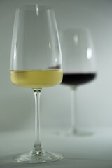 vasos de cristal sobre fondo blanco con reflejos, de vino blanco y vino tinto 