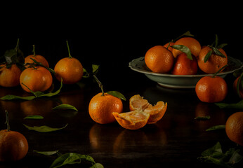 Still life of mandarins and leaves against black background