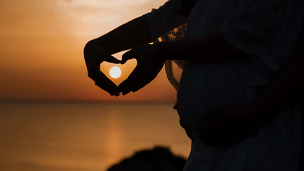 Heart at sunset.  Waiting for a baby, silhouette photo of pregnancy