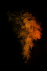 Fragment of orange magic curly steam smoke isolated on a black background, close-up. Create...