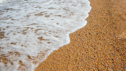 White sea foam on a sandy beach on a clear summer day